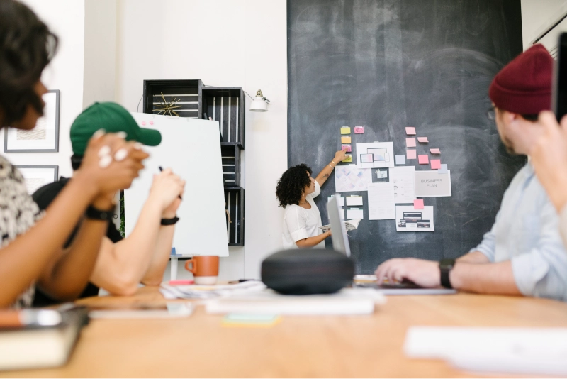 Key features of on-demand apps include user registration, map integration, and real-time tracking Team collaborating on on-demand app features on board