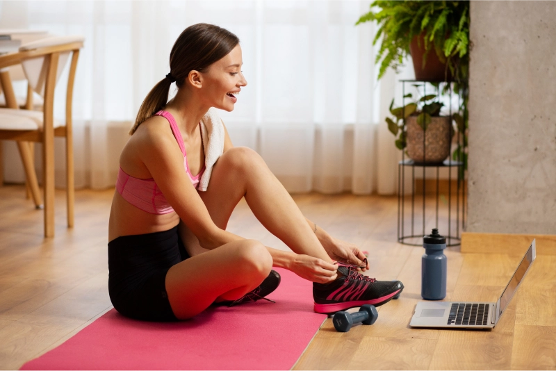 On-demand wellness and fitness apps offer personalized workouts and expert guidance Woman tying shoes before online workout session
